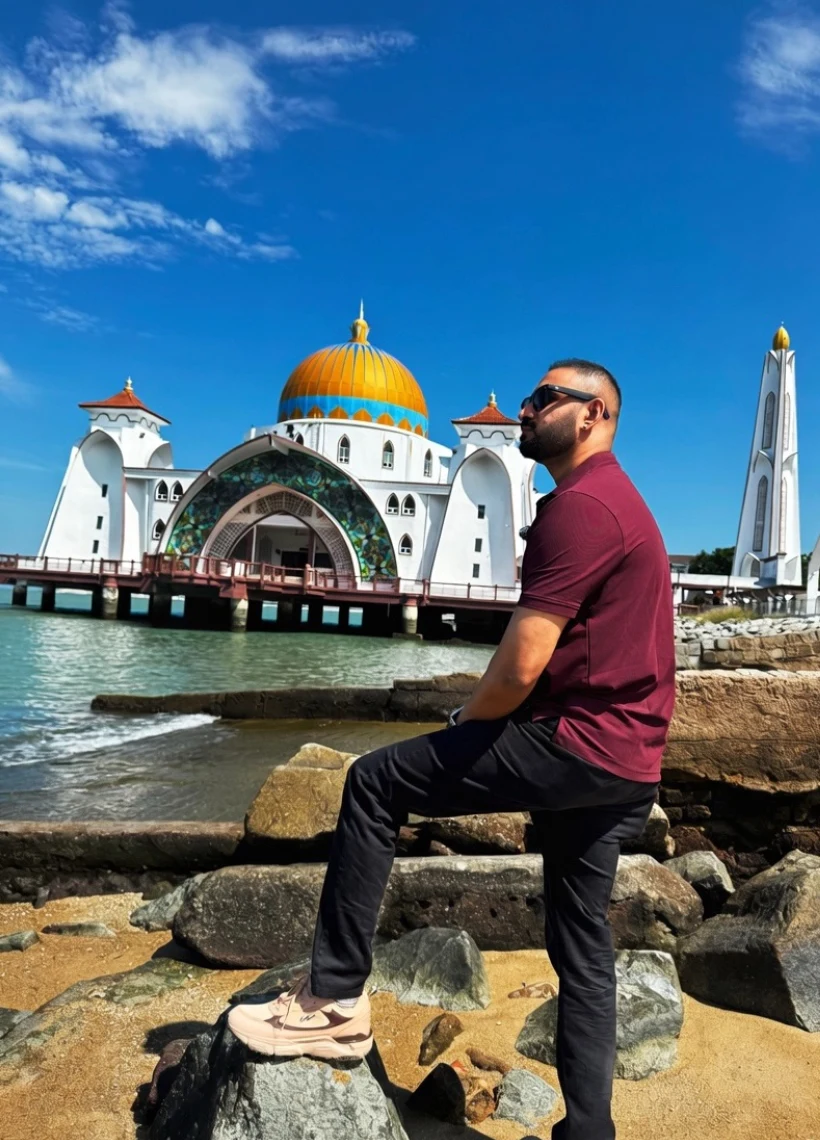 Rahul Warrier on coastal rocks overlooking the Malacca Straits Floating Mosque