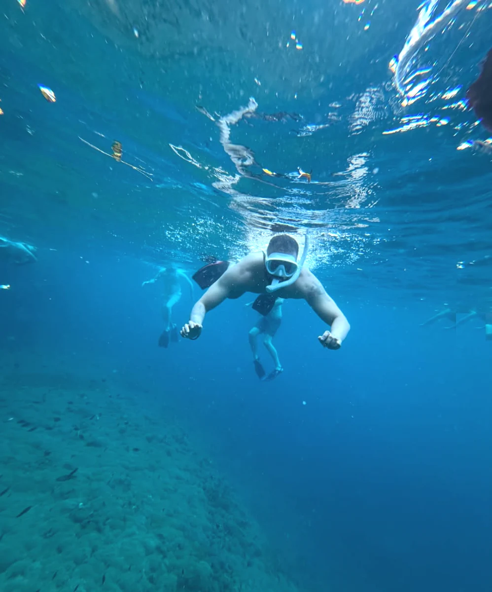 Rahul Warrier snorkeling in the turquoise ocean waters of Nusa Penida with coral reef below